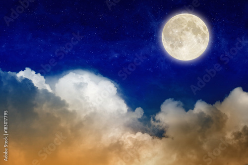Full moon rising above glowing clouds in night sky
