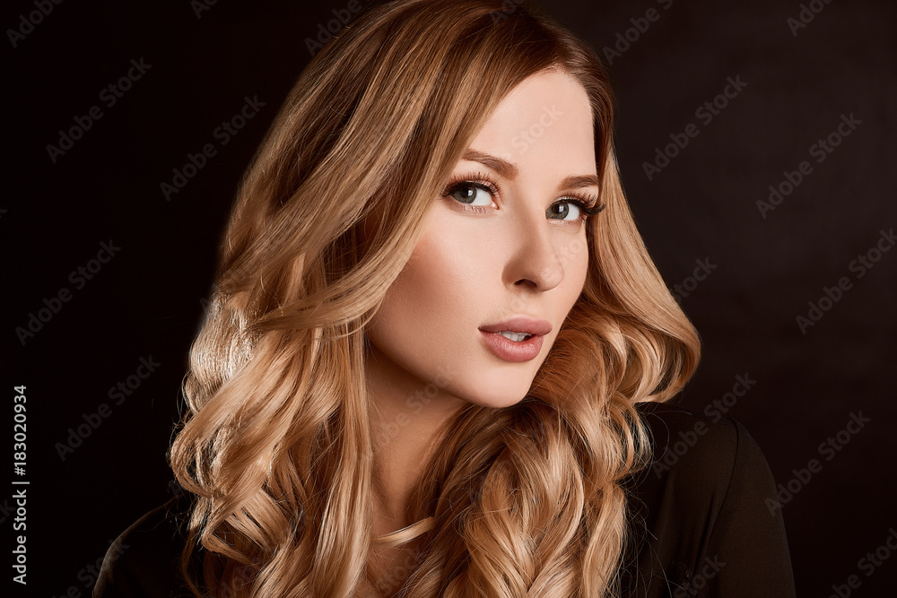 Fototapeta premium Beautiful blonde woman with curly hair posing on black background