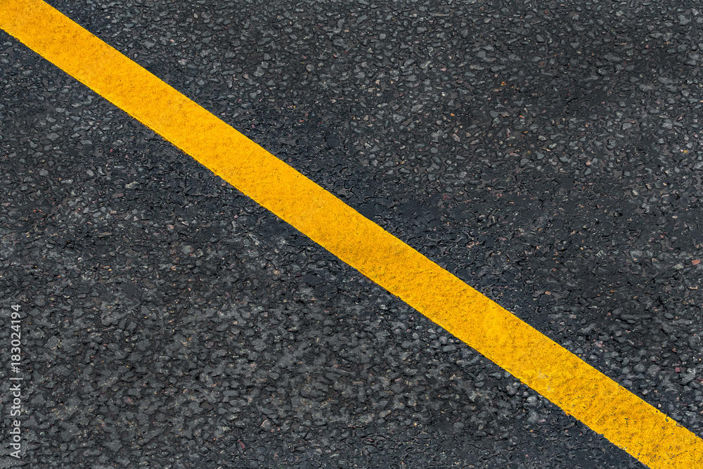 Yellow diagonal marking line on the asphalt road (background, texture, abstract)