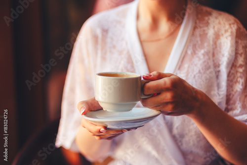 Soft photo of fresh young woman in pink tender bathrobe drink tea or coffee and smiling. Pretty girl enjoying early sunny morning. Closeup. Vintage tonted photo.