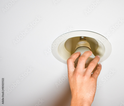 hand of young man changing a compact flourescent light bulb