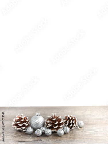 Christmas holiday scene with frosted pine cones and ornaments on rustic wood table and white background.  Room for text copy space.  