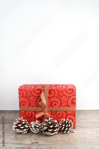 Christmas scene including wrapped package and pine cones on rustic wood table and white background and copyspace