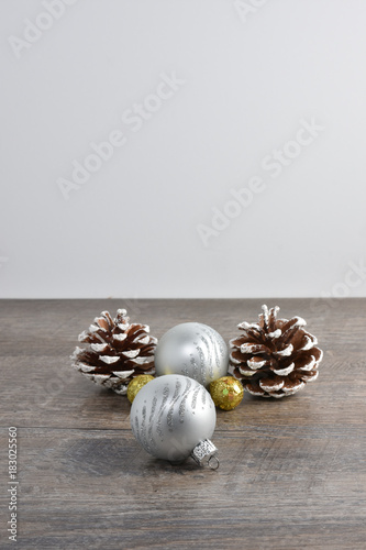 Christmas scene including pine cones and ornaments on rustic wood table and white background with copy space.  White message board background.