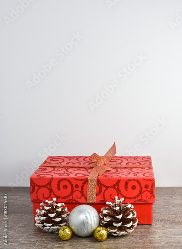 Christmas scene including wrapped package, pine cones, and ornaments on rustic wood table and white background and copyspace