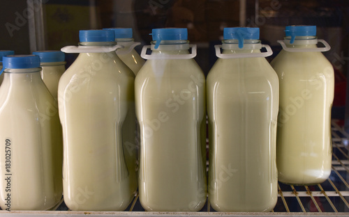 Glass quart and half gallon containers of white milk on grocery store shelf