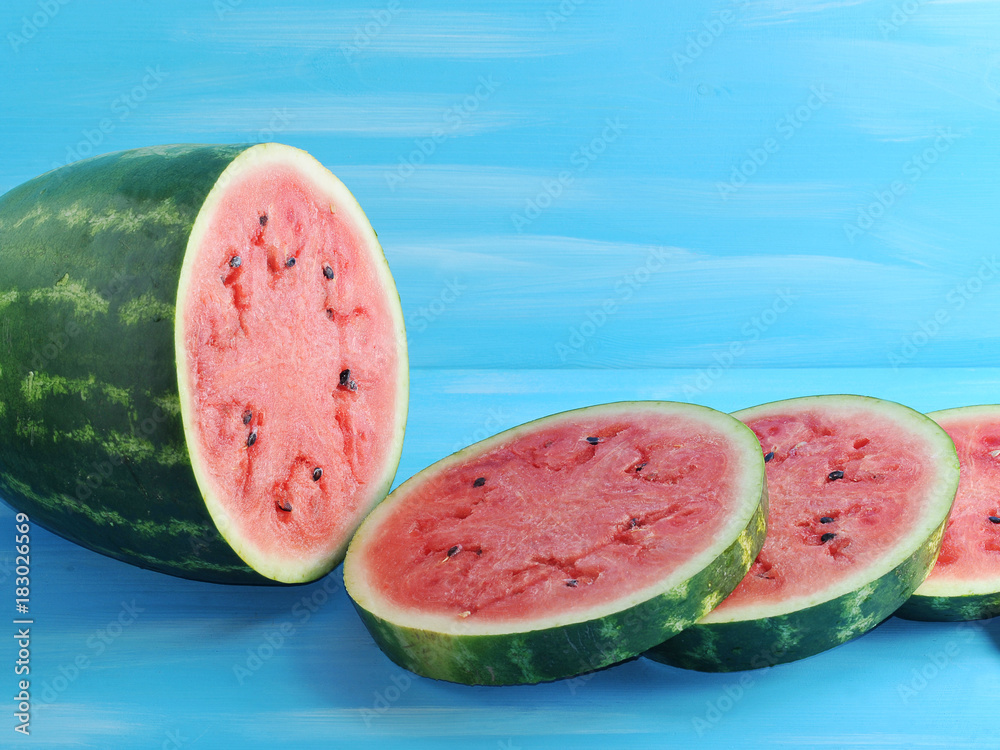 green watermelon cut into round slices on a blue  background