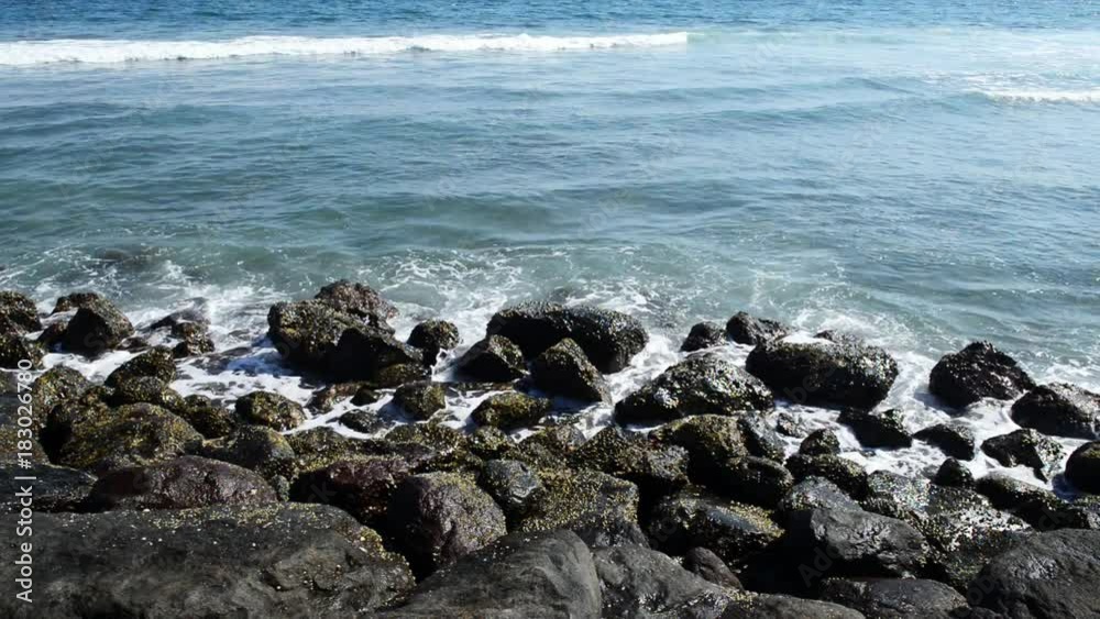 A huge wave hits the rocks. Waves hitting rocks on a tropical beach forming a splash shape. Powerful Waves on a rocky beach. A huge wave hits the rocks. Waves hitting rocks on a tropical beach forming a splash shape. Powerful Waves on a rocky beach.