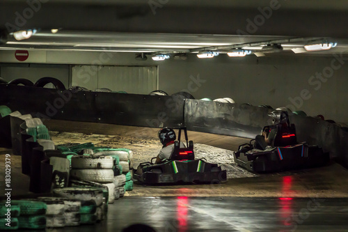 Two carts racing in the curve on the indoor track, view from the back