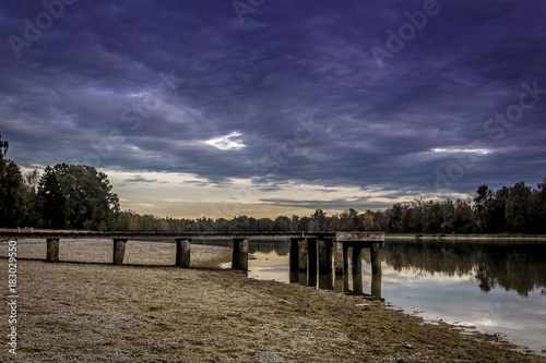 Evening autumn atmosphere at lake Kuhsee in Germany with small pier and colorful trees and nice reflection on water photo