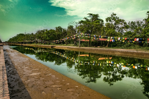 green watercourse with reflections in sacred land in lumbini nepal. photo