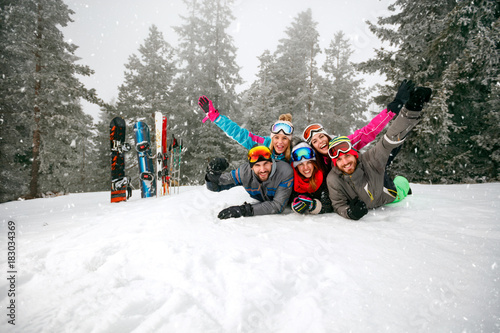 cheerful skiers lying on snow and having fun