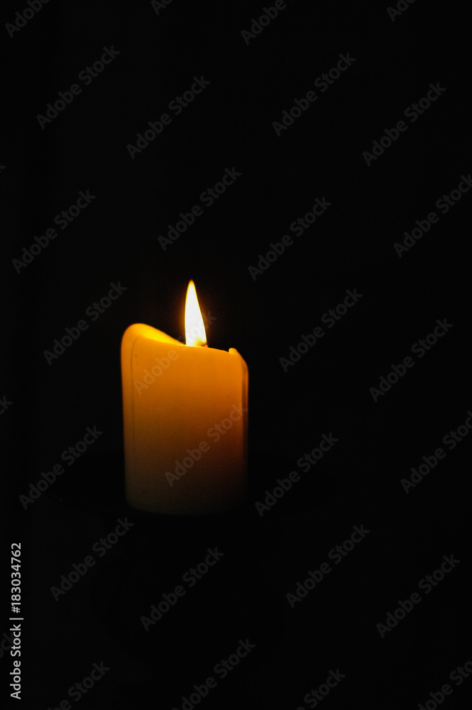 Lighted yellow candle with yellow flame burning as prayer candle in