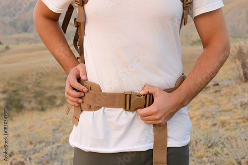 a young man demonstrates fastex buckle in action from the waist belt of a backpack see more