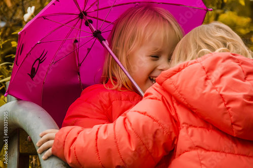 two little girls having fun under an umbrella, in the autumn afternoon photo