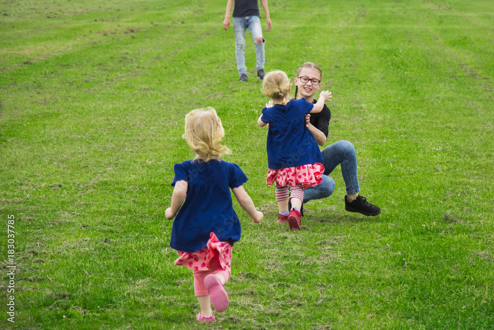 children fun running around the green field. two girls play with their older sister children fun running around the green field. two girls play with their older sister