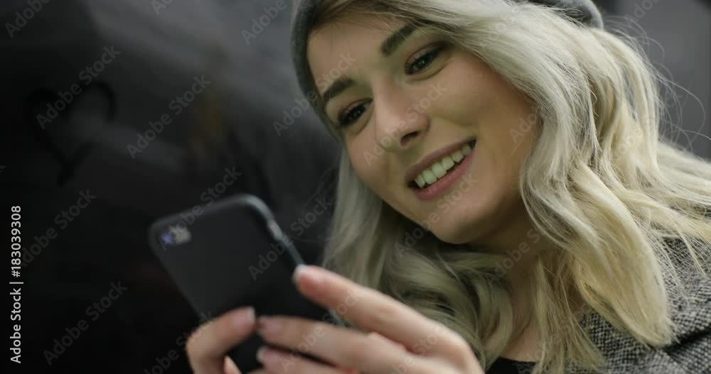 Close-up portrait of a smiling cute girl browsing and typing message on her phone while travelling on the public transport. Close-up portrait of a smiling cute girl browsing and typing message on her phone while travelling on the public transport.