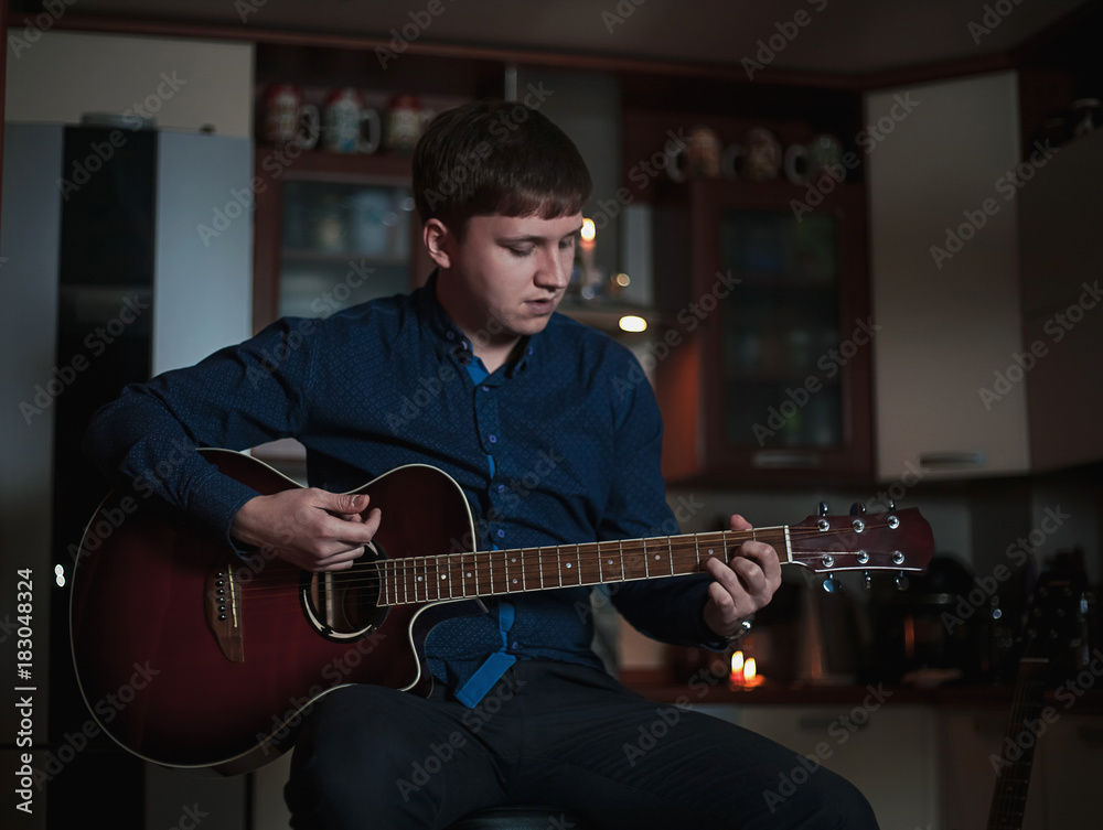 Obraz premium The Guitarist Guy plays the guitar in a bar in a beautiful setting on a high bar stool
