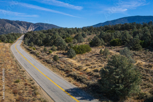 Asphalt road bends into a wood of evergreen trees in southern California's Los Padres National Forest. © kenkistler1