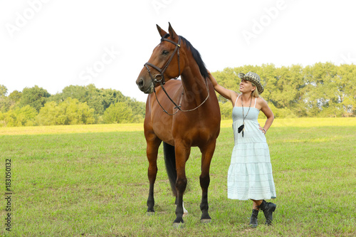 Woman with straw hat with horse in pasture
