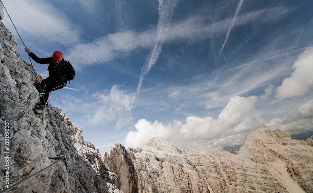 Fototapeta premium young female climber on a Via Ferrata in the Italian Dolomites with a fantastic view and background