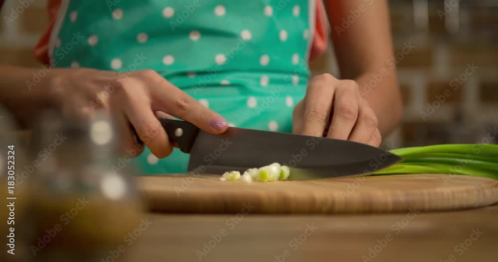 Woman hand prepares salad at home kitchen 4k close-up video. Female cooking side dish: cutting green onion, knife slicing greenery, vegetables on table. Healthy food Woman hand prepares salad at home kitchen 4k close-up video. Female cooking side dish: cutting green onion, knife slicing greenery, vegetables on table. Healthy food