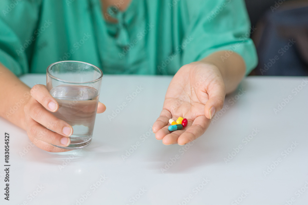 The patient handles the cup to prepare to take some medicine and a glass of water. The patient handles the cup to prepare to take some medicine and a glass of water.
