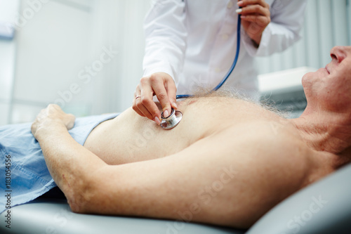 Doctor listening to heartbeat of senior patient with stethoscope