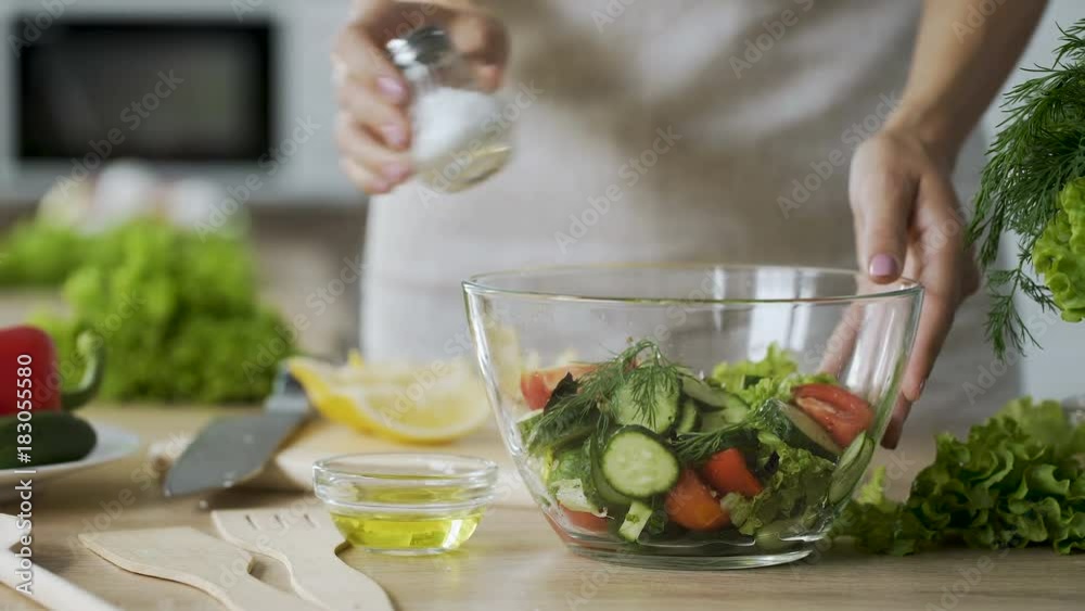Woman adding salt in salad with vegetables in glass bowl, close-up video Woman adding salt in salad with vegetables in glass bowl, close-up video