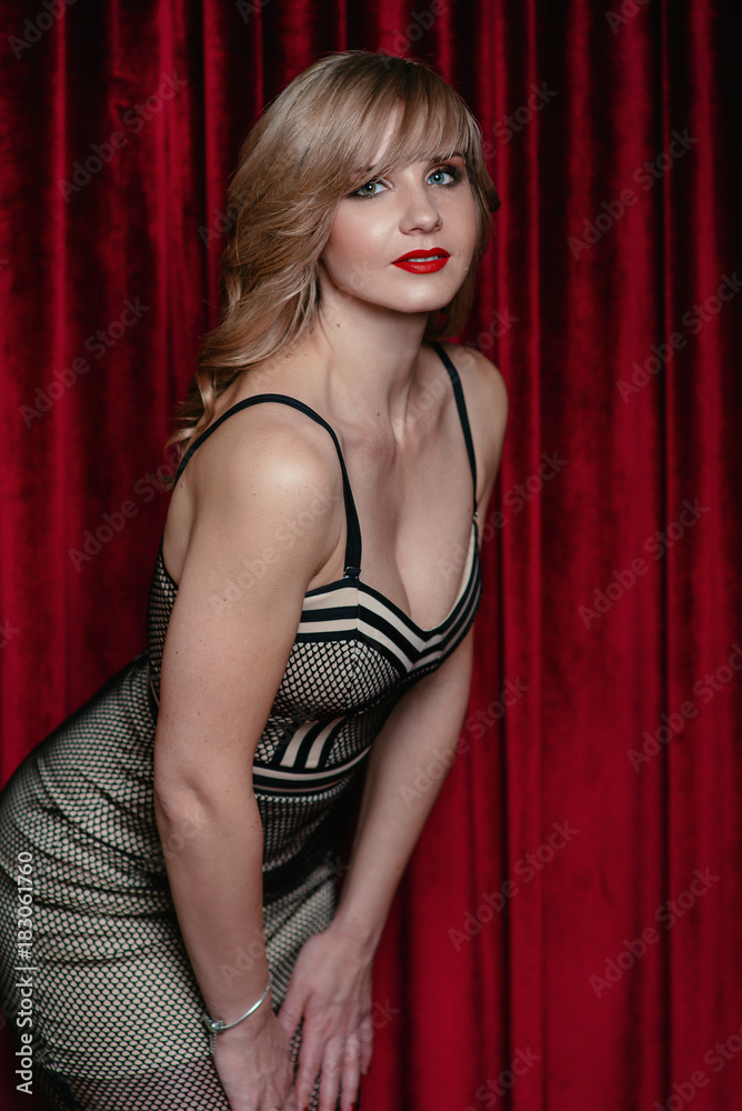 beautiful attractive young woman with make up in stylish dress stending near the red velvet curtain in the evening on important event in the theater beautiful attractive young woman with make up in stylish dress stending near the red velvet curtain in the evening on important event in the theater