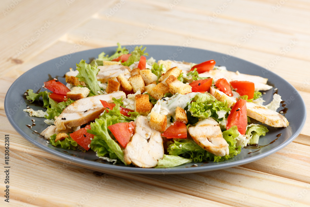Caesar salad in the grey plate on the wooden table Caesar salad in the grey plate on the wooden table
