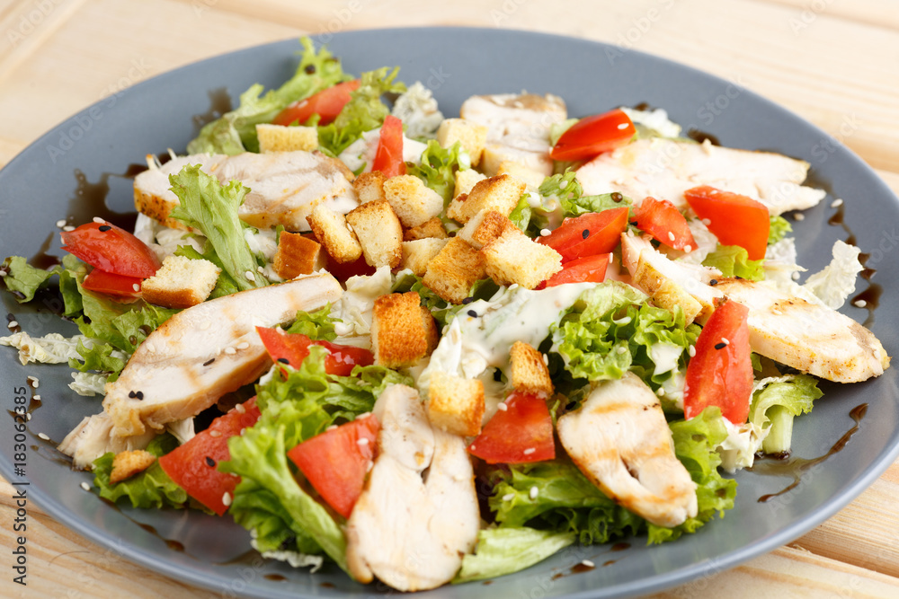 Caesar salad in the grey plate on the wooden table Caesar salad in the grey plate on the wooden table