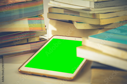 tablet with green screen in the stack of books