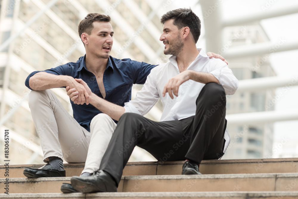 Two happy businessmen sitting down on concrete stairs shaking hands. Two happy businessmen sitting down on concrete stairs shaking hands.