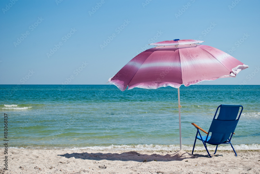 Blue beach chair and pink big outdoor umbrella for shade on the shore of the blue sea Island of sand in the water blue sky sea wave beautiful landscape summer vacation beach sand weekend rest