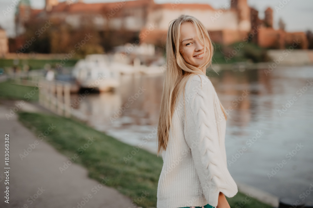 Beautiful blonde young woman walking beside the river at sunset have fun smile and play on camera Beautiful blonde young woman walking beside the river at sunset have fun smile and play on camera