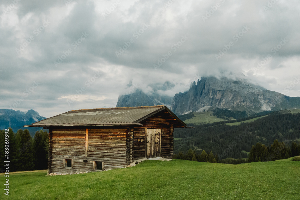 Old cabin with moody view to mountain Plattkofel and Langkofel on Alpe di Siusi in the Dolomites