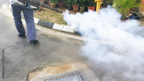 Technician fogging into drain to kill aedes mosquito, carrier of dengue and zika fever virus 

 photo