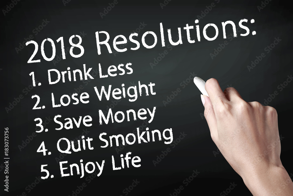 Hand holding a chalk and writing 2018 goals Hand holding a chalk and writing 2018 goals