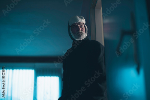 Man in woolen cap intruding dark living room.