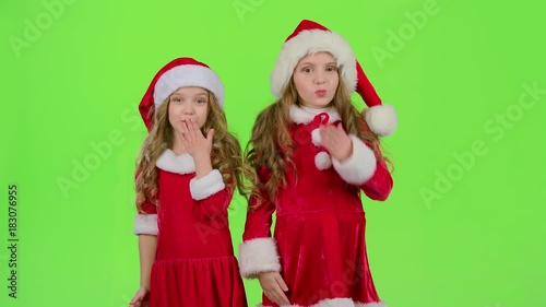 Children in red Christmas caps send air kisses. Green screen. Slow motion photo