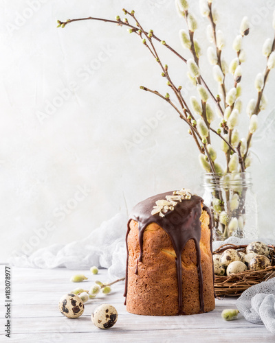 Easter orthodox sweet bread, kulich with chocolate glaze and quail eggs on light background. Easter holidays breakfast concept with copy space.