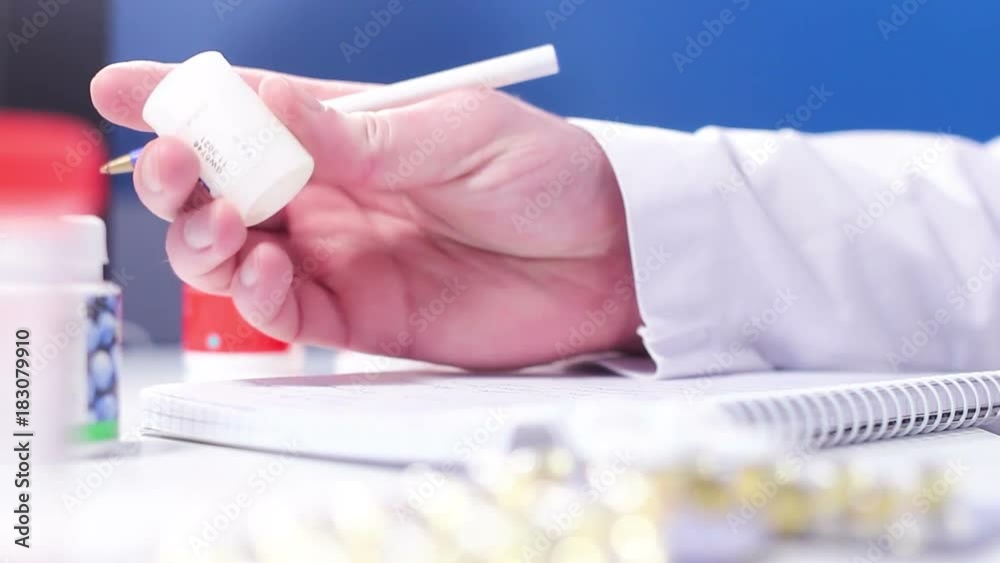 Doctor pharmacist evaluates bottle with tablets and wrote in a note results Doctor pharmacist evaluates bottle with tablets and wrote in a note results
