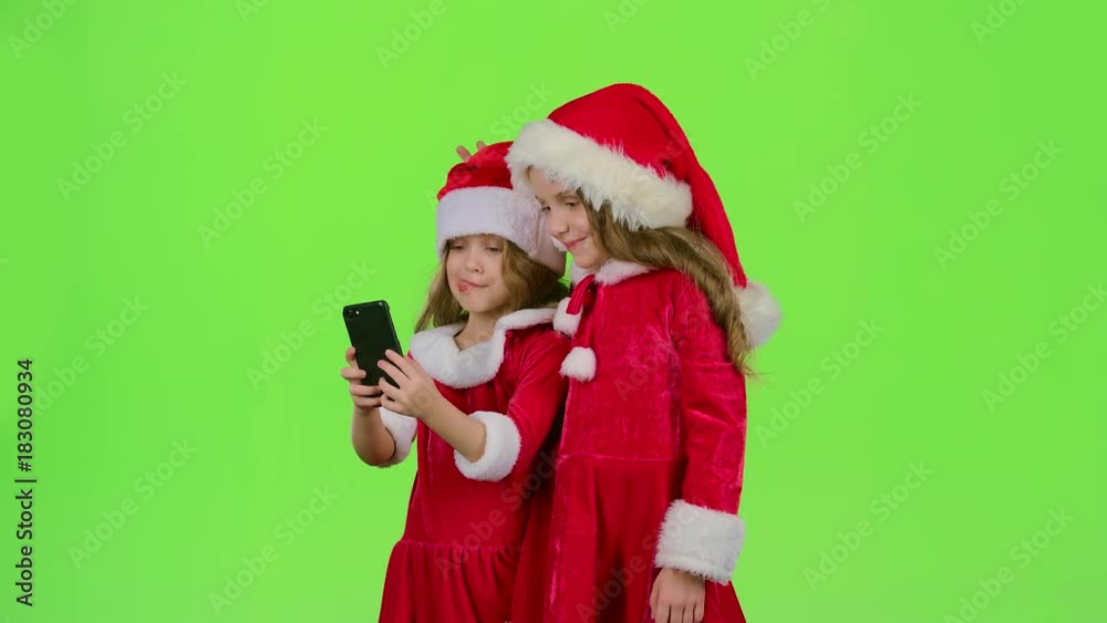 Children little ones show the tongue and make faces and make selfies on the smartphone. Green screen. Slow motion Children little ones show the tongue and make faces and make selfies on the smartphone. Green screen. Slow motion