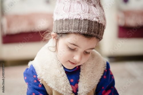 Small girl wearing woolen hat during winter inside house 