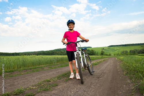 Fototapeta Naklejka Na Ścianę i Meble -  Sporty girl with bicycle in green field.