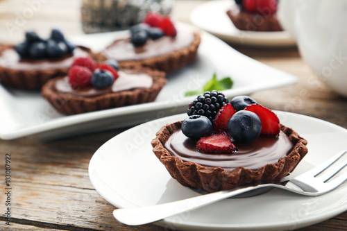 Fotografiet Chocolate tartlets with berries on grey wooden table