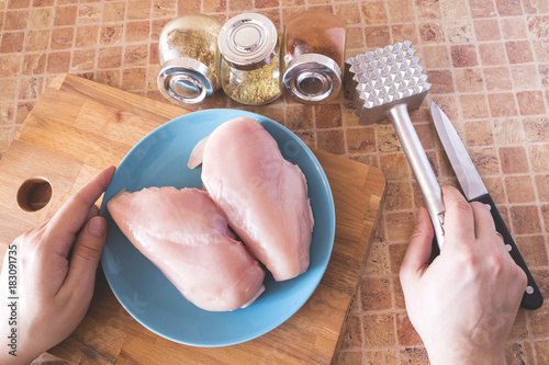 top view of process of cooking chicken breast in the kitchen with meat tenderizer hammer and knife photo