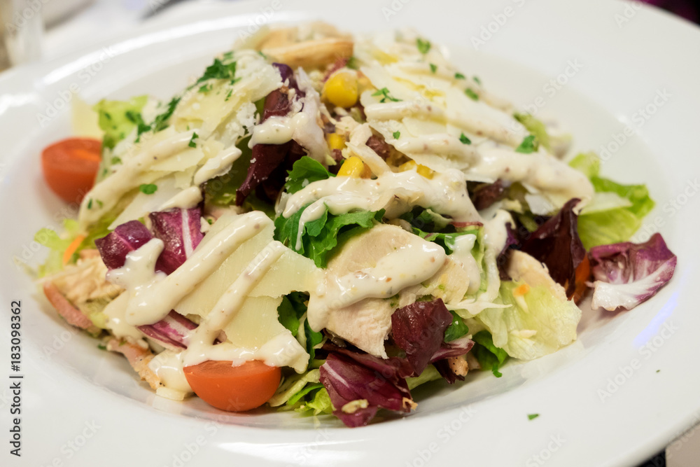 Caesar salad with roasted chicken breast, parmesan cheese, lettuce leaf, cherry tomatoes, corn and cheese sauce