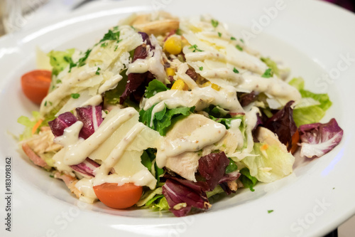Caesar salad with roasted chicken breast, parmesan cheese, lettuce leaf, cherry tomatoes, corn and cheese sauce